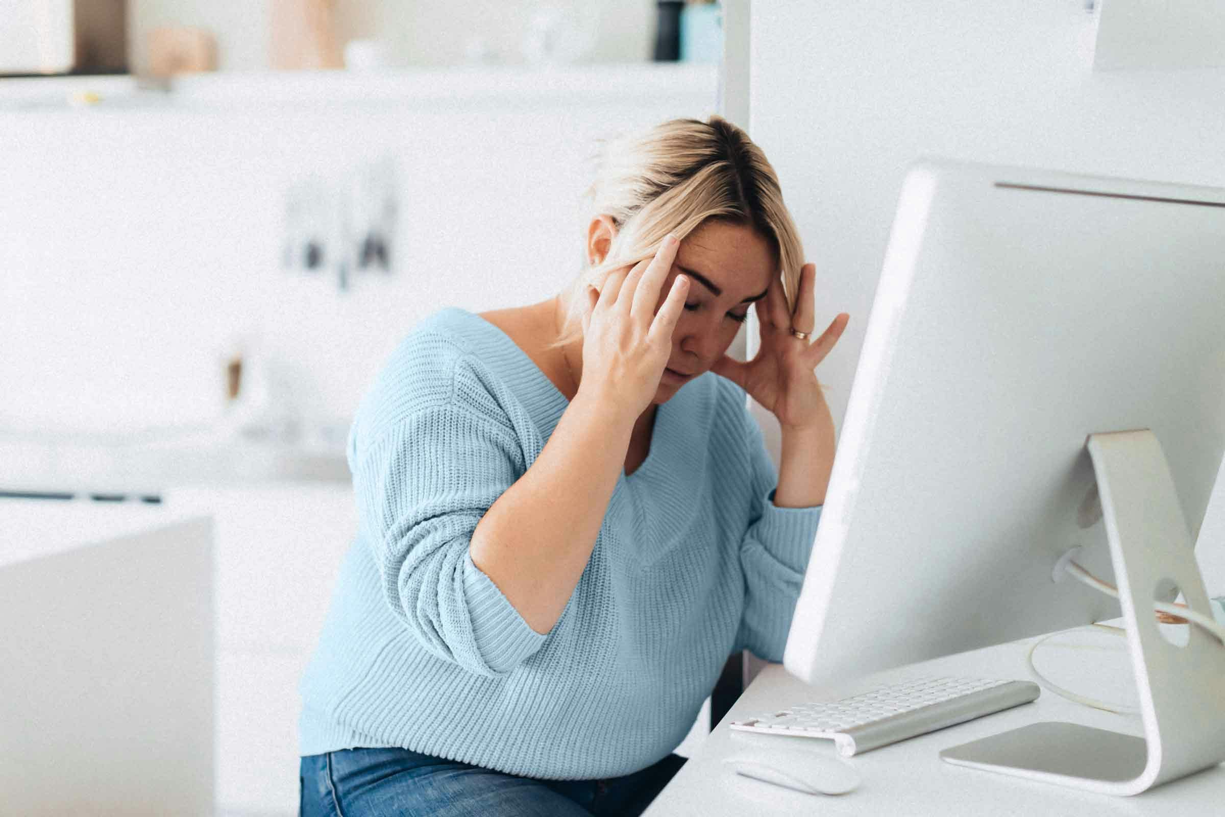 Woman working on desktop suffers from headache caused by anxiety