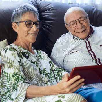 Elderly couple looking at an iPad and smiling