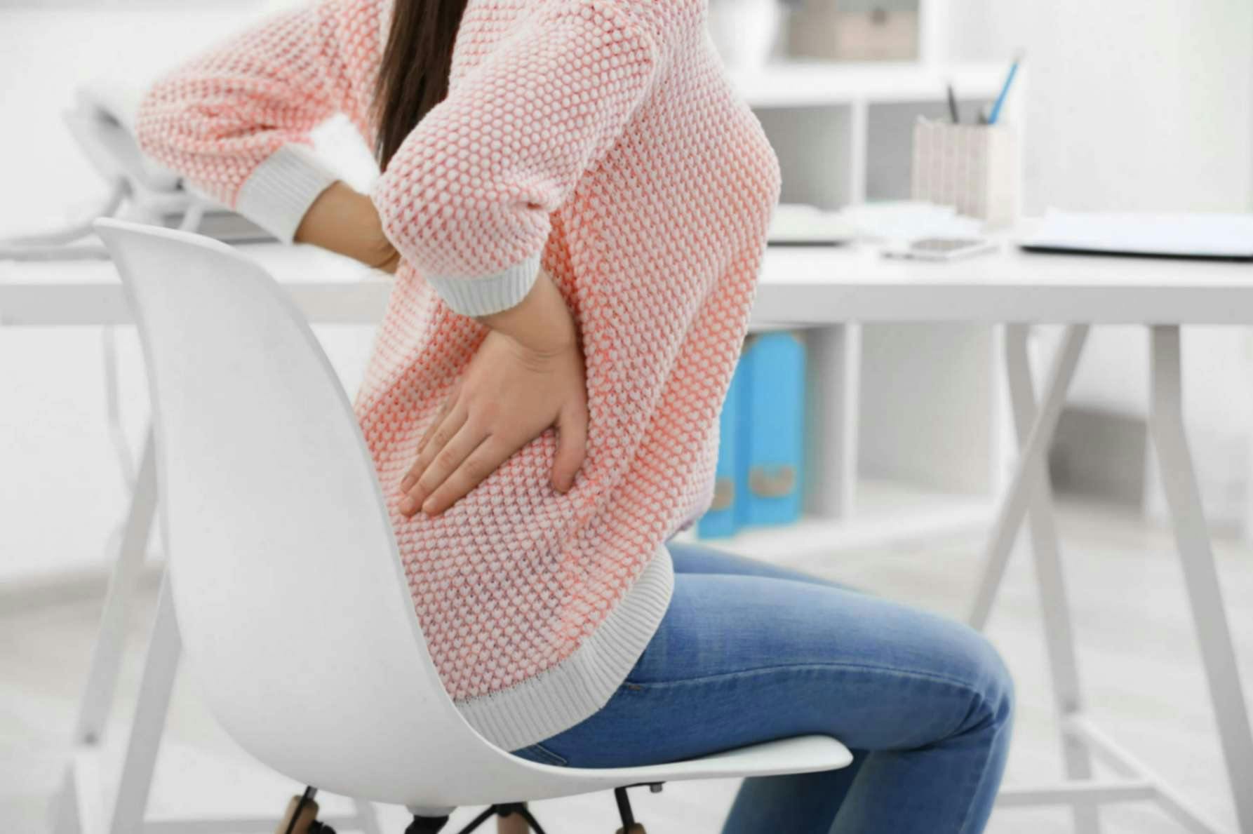Woman with lower back pain sitting on a chair