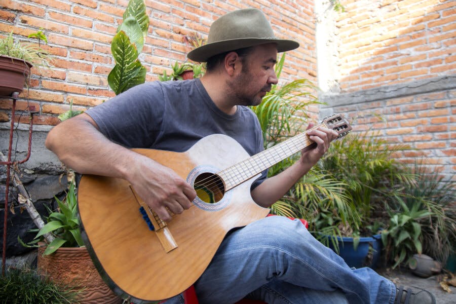 Man wearing a fedora and playing the guitar