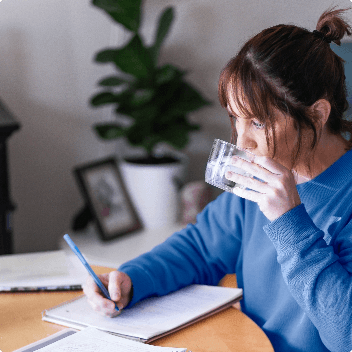 Young woman sipping water while doing homework
