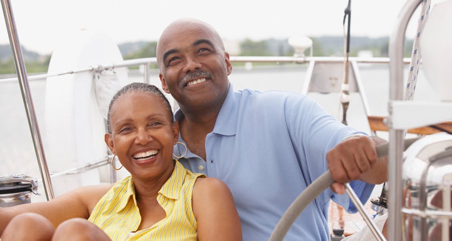 Older couple driving a boat, smiling