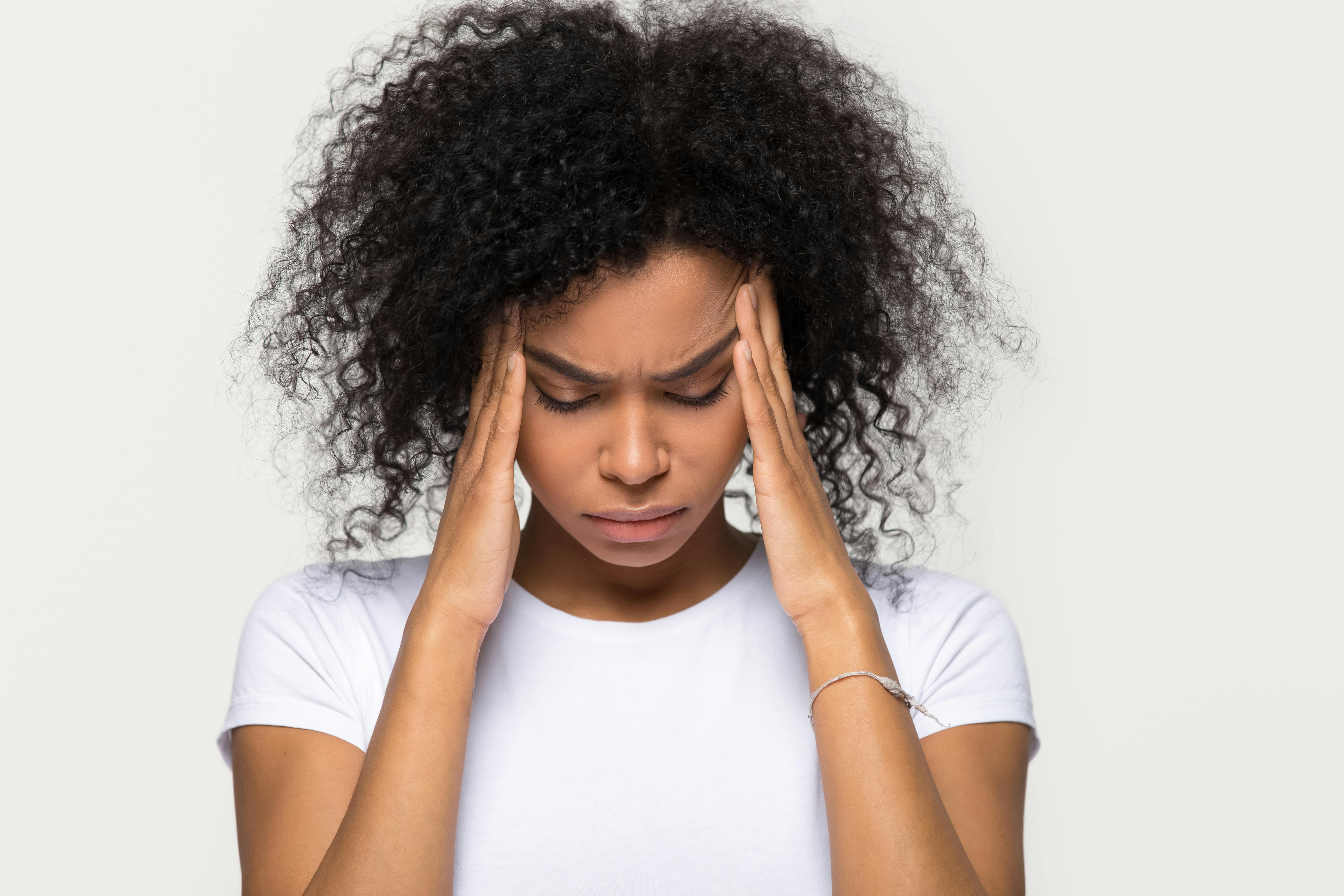 Woman suffering from a tension headache presses her hands to her head