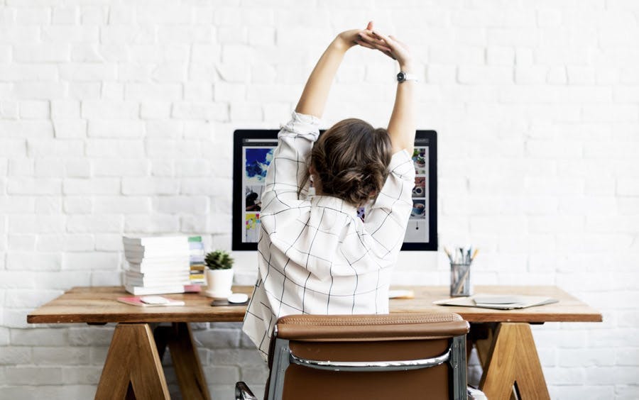 Woman stretching arms at her desk