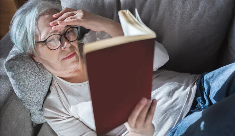 Femme lisant un livre sur un canapé