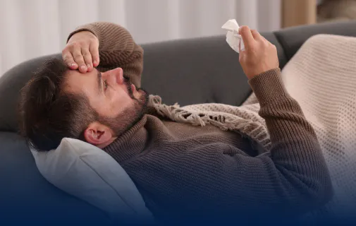 Homme couché sur un canapé et se tenant la tête, en proie à une douleur