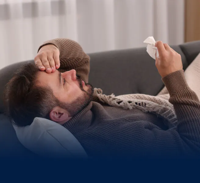 Homme couché sur un canapé et se tenant la tête, en proie à une douleur