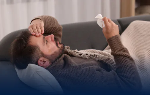 Homme couché sur un canapé et se tenant la tête, en proie à une douleur