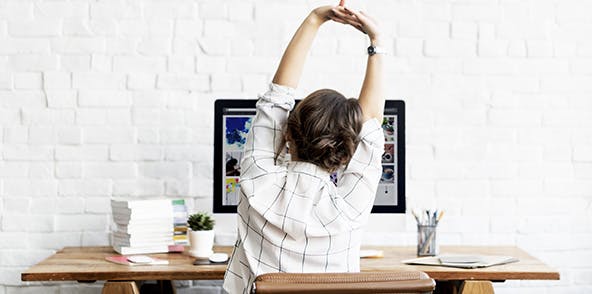 Woman stretching arms at her desk
