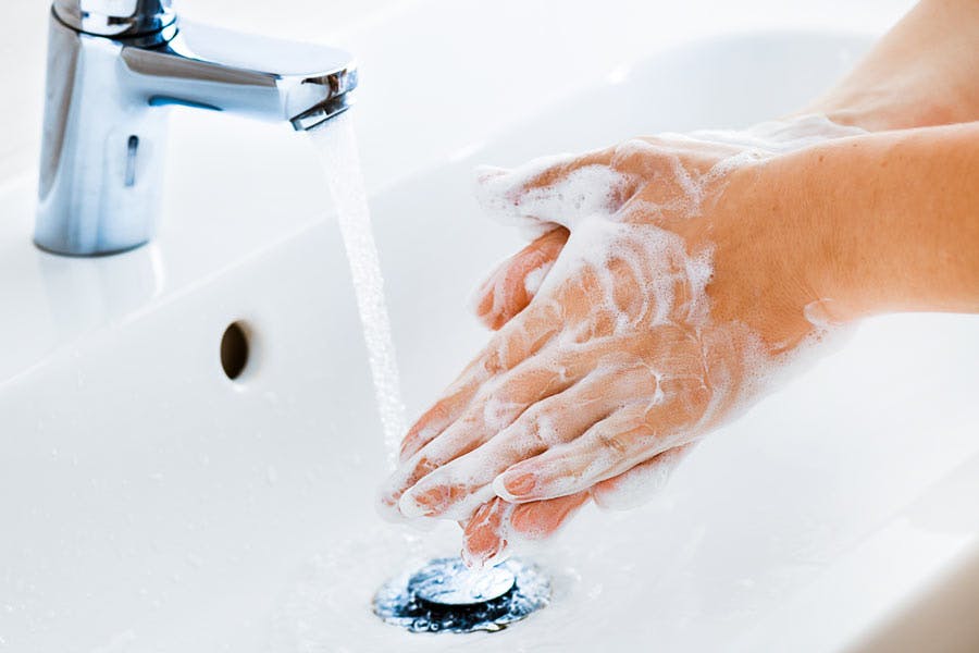Woman washing her hands in sink with soap.