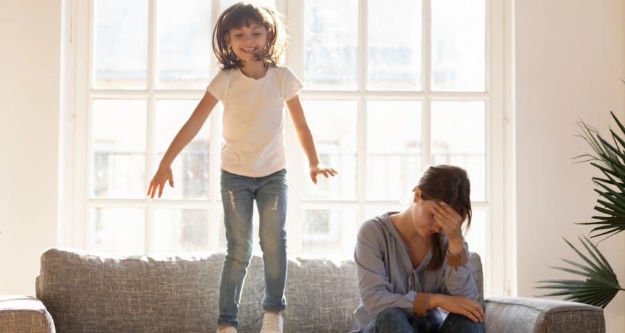 Mujer te toca la cabeza en señal de dolor mientras niña salta