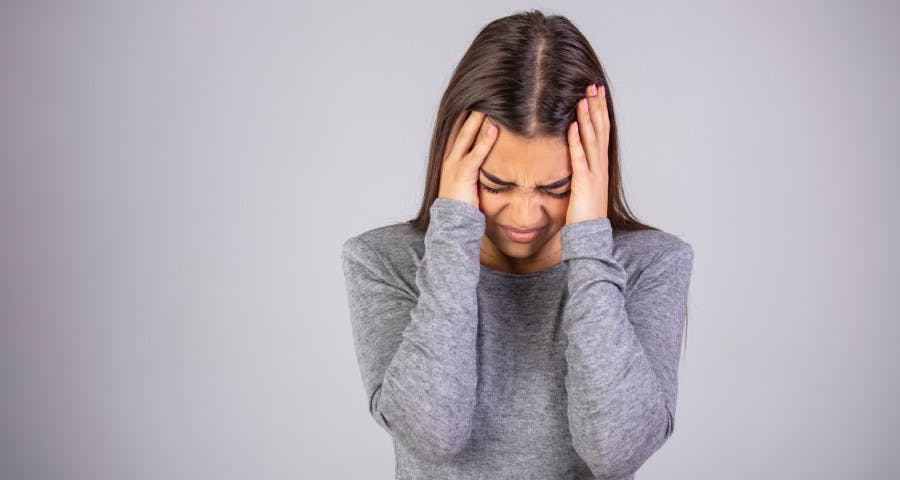 Mujer tomandose la cabeza en señal de dolor