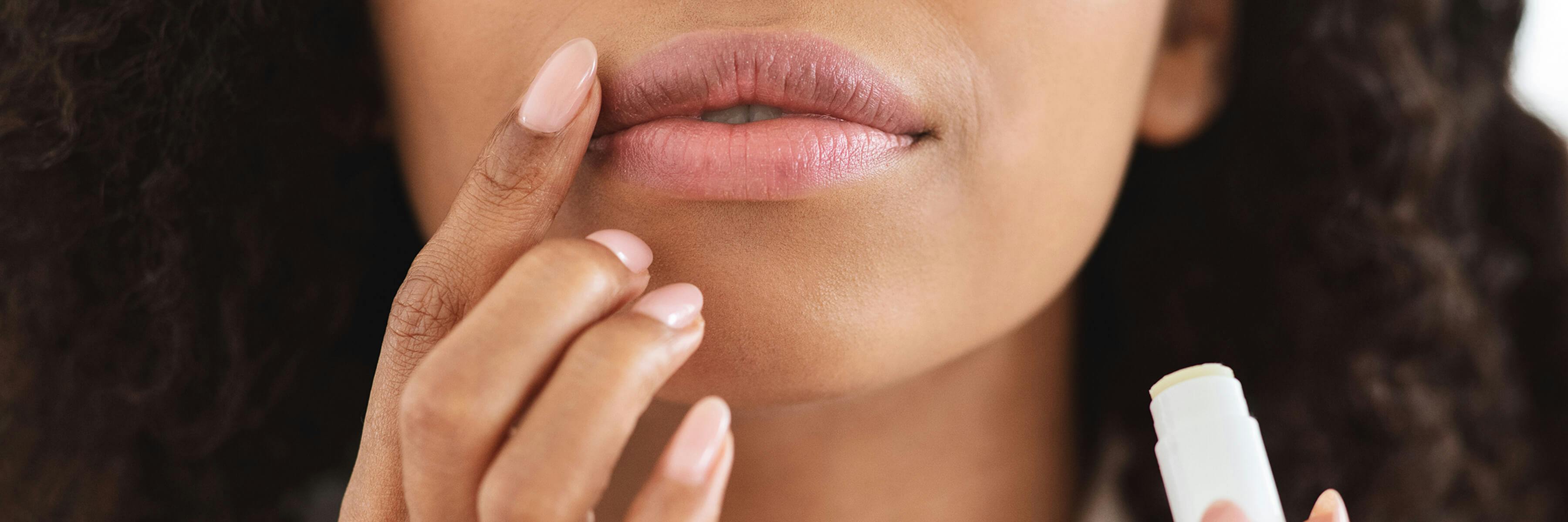 woman applies lip balm to lip