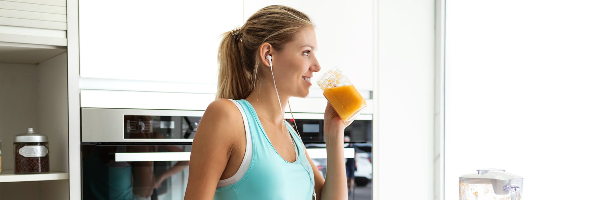 Athletic woman drinking a smoothie and listening to music