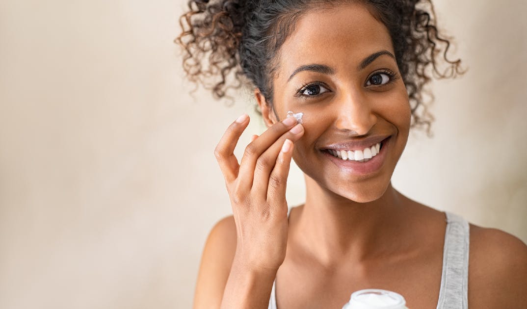 woman rubbing skin moisturizer into her cheek