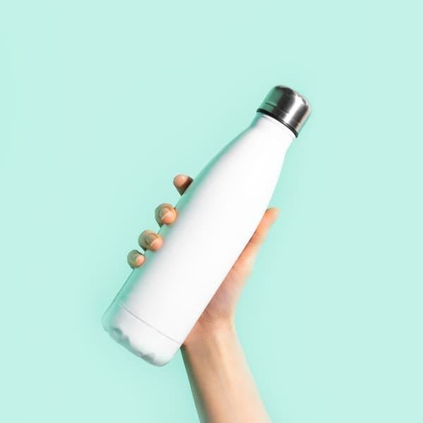 Hand holding water bottle against colorful background