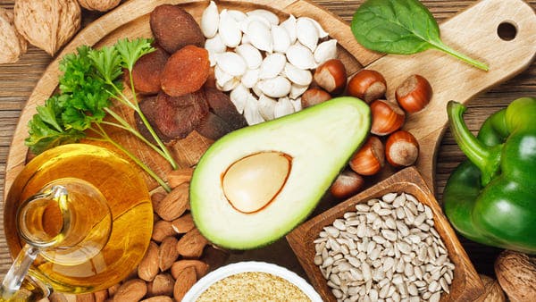 avocado, sunflower seeds, hazelnuts, and other foods rich in vitamin e on wooden plate