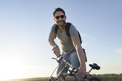 Guy with bike in front of sun