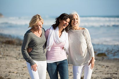 Three elderly ladies walking on the beach.