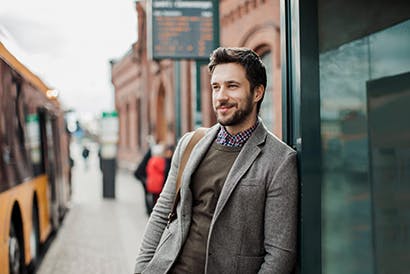 Man with a beard standing casually at a bus stop