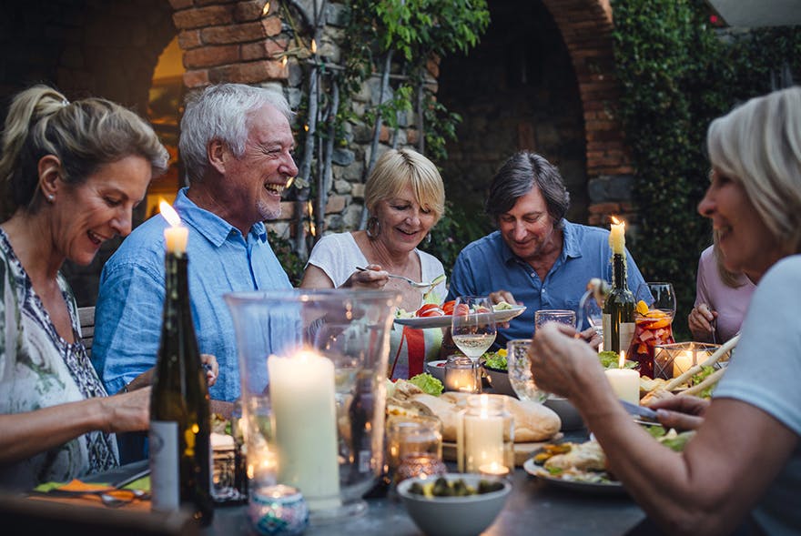 Gruppe älterer Leute sitzt am Tisch zum Essen zusammen.