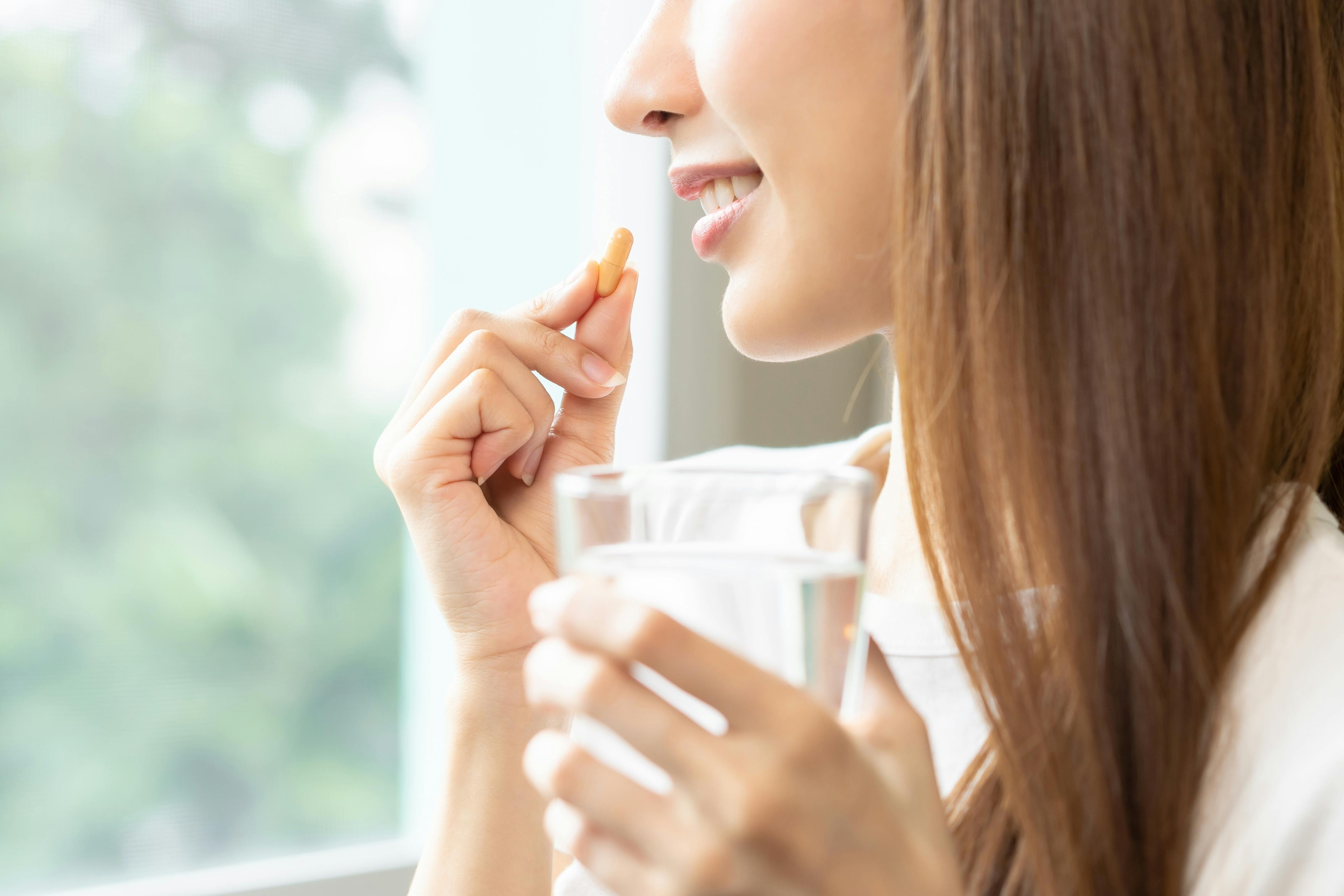Woman holding vitamin c pill and glass of water