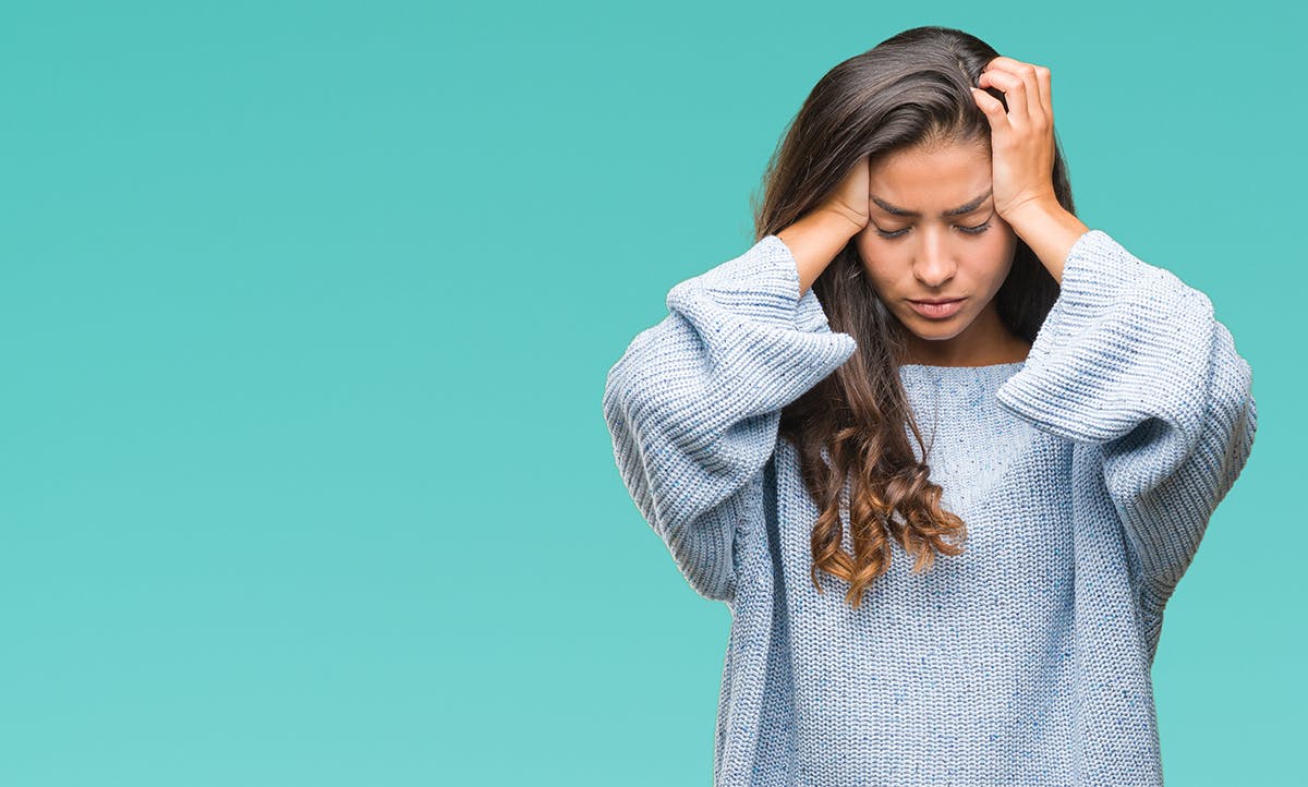 A visibly stressed woman in a blue sweater holding her head A visibly stressed woman in a blue sweater holding her head