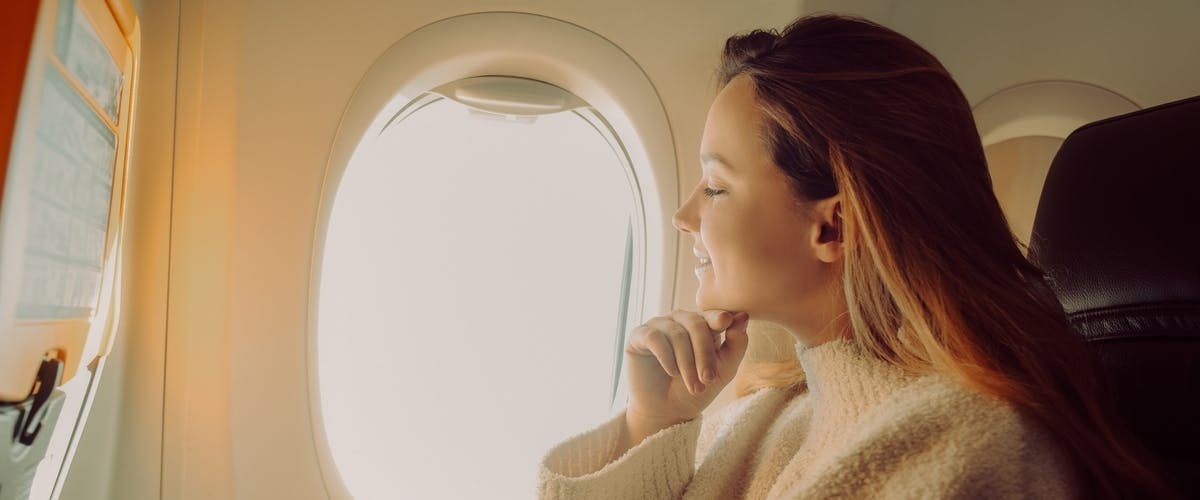 A traveling woman looking out of an airplane window