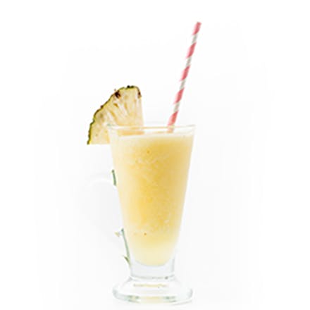 Tropical Medley Smoothie in glass with striped straw and pineapple wedge