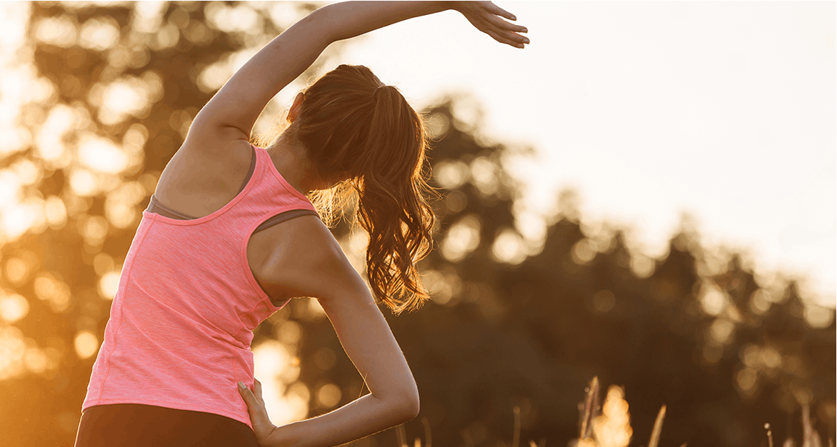 A woman in a pink tank top stretches before a run A woman in a pink tank top stretches before a run