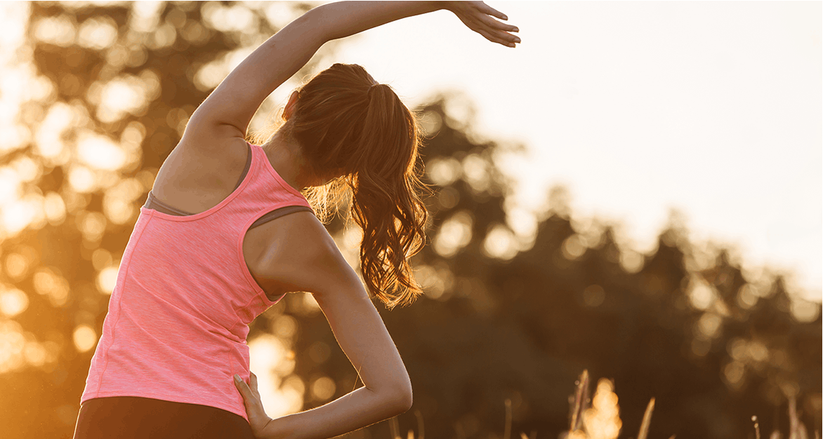 A woman in a pink tank top stretches before a run