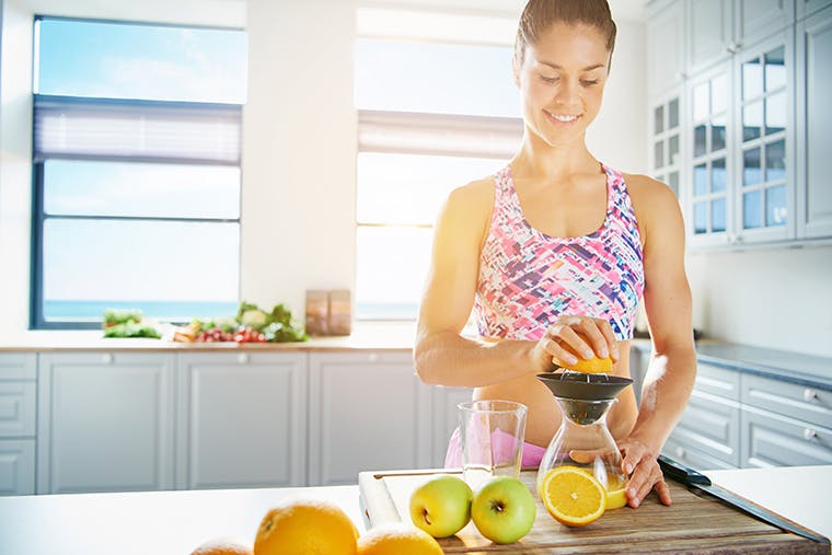 Woman in athletic clothing juicing oranges