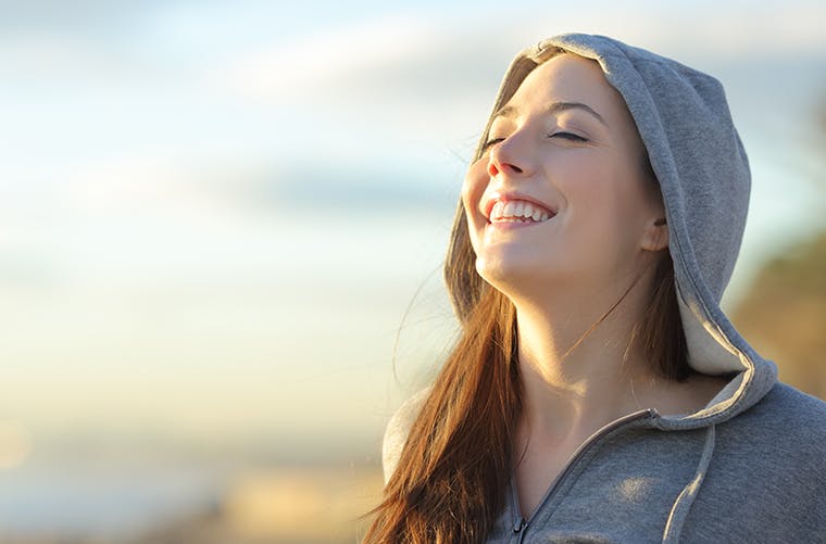 Woman in hooded sweatshirt smiling outdoors