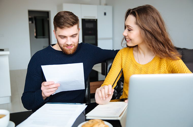 Happy young couple calculating bills at home