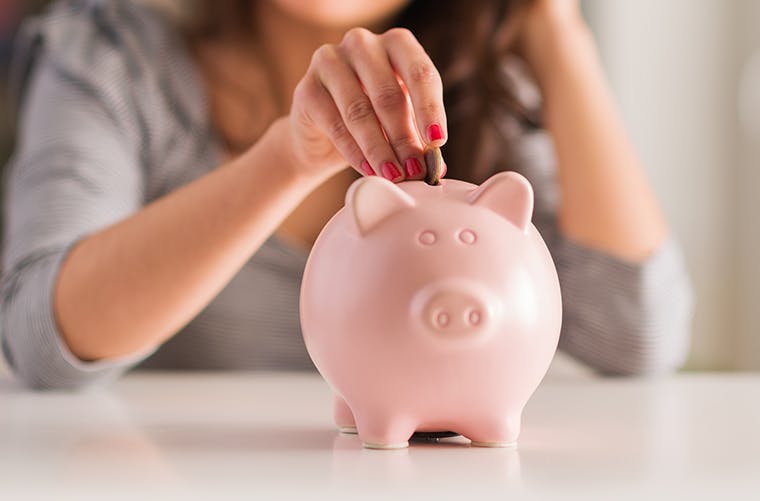 Woman putting coin in piggy bank