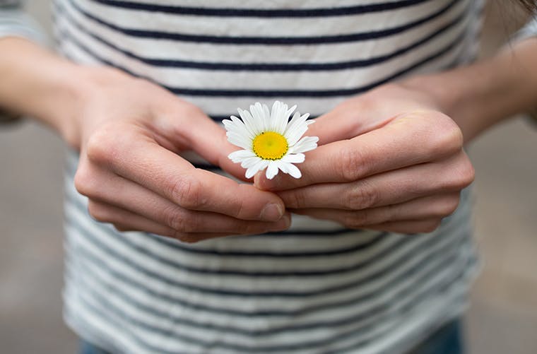 Woman in striped shirt holding white daisy