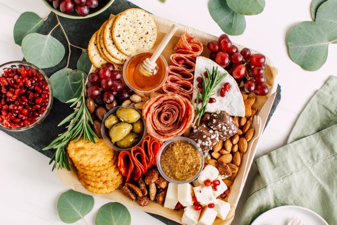 Charcuterie board, bread, olives, peanuts and glass bottle