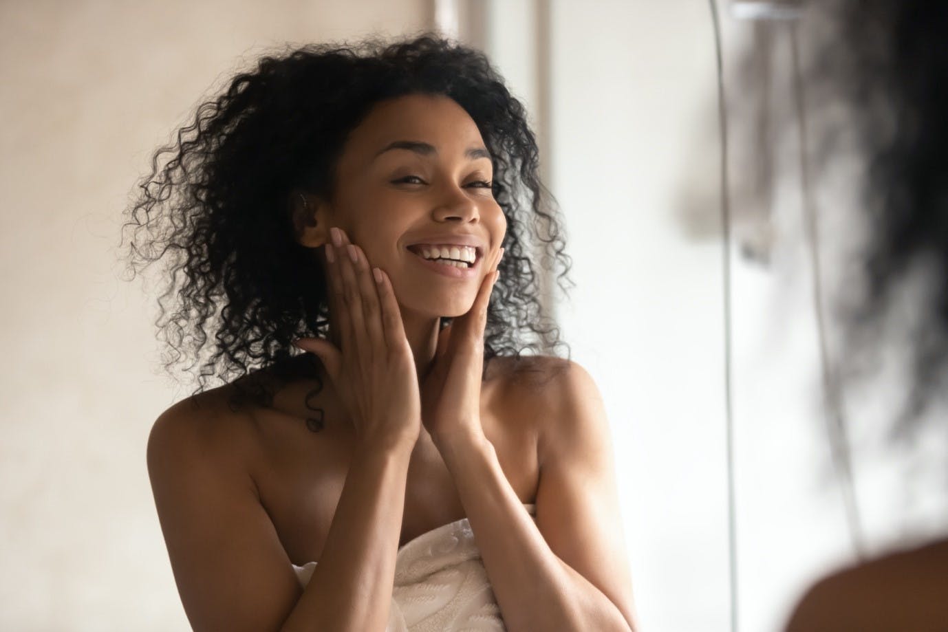 Woman in towel smiles in mirror after a shower