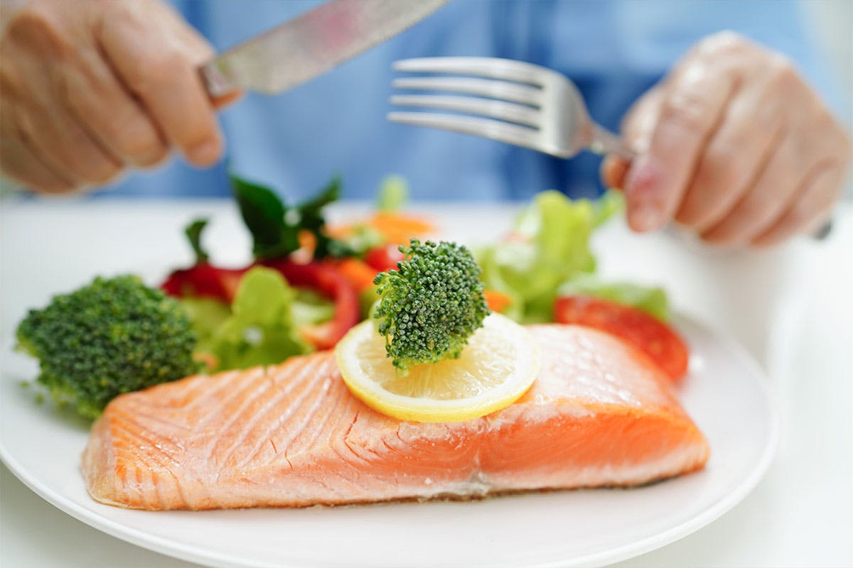 Person eating salmon, a source of vitamin D Person eating salmon, a source of vitamin D