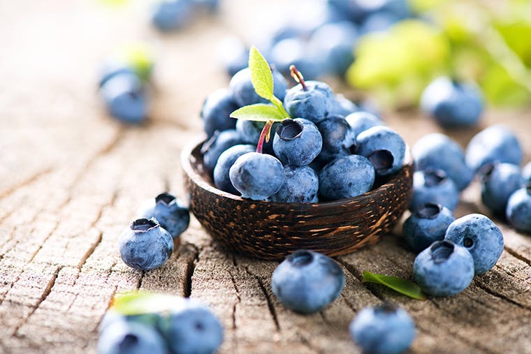 Small brown bowl filled to the top with freshly picked blueberries