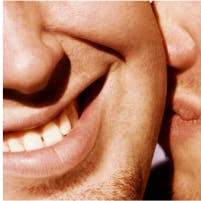 Close-up of two smiling people, focusing on their mouths and cheeks, showing expressions of intimacy