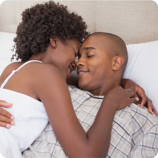 Couple lying on a bed, laughing and looking into each other's eyes