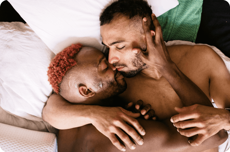 Two men lying in bed, holding each other closely and sharing an intimate moment.