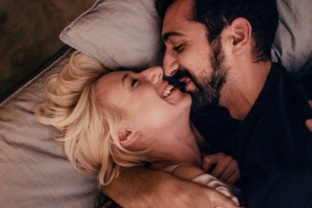 Couple lying on a bed, laughing and looking into each other´s eyes