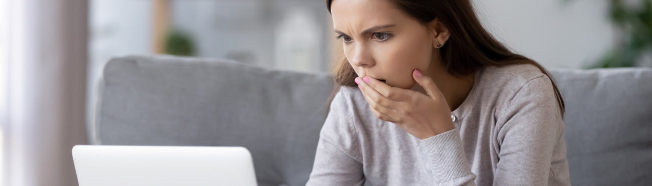 woman touching mouth looking at computer