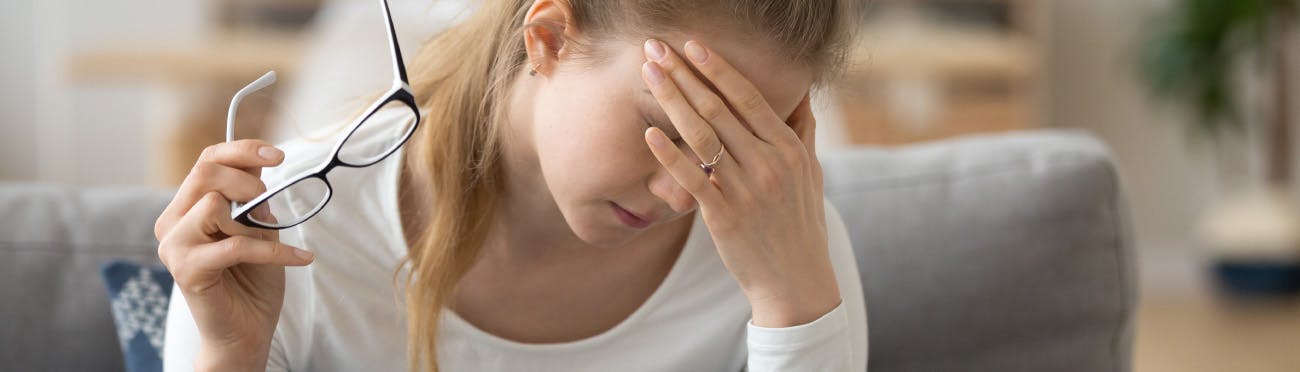 Woman with glasses wondering if she has a headache or a migraine