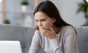 woman touching mouth looking at computer