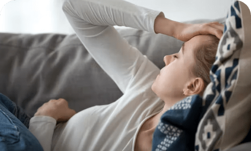 Young woman on couch suffering from migraine and fever