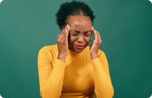 Woman wearing a yellow jacket suffering with a migraine