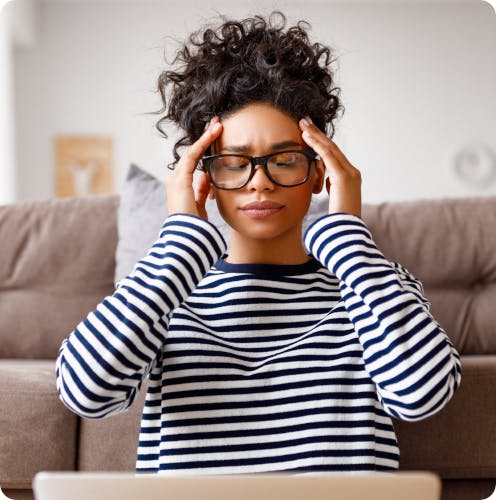 Woman sitting at computer struggles with migraine